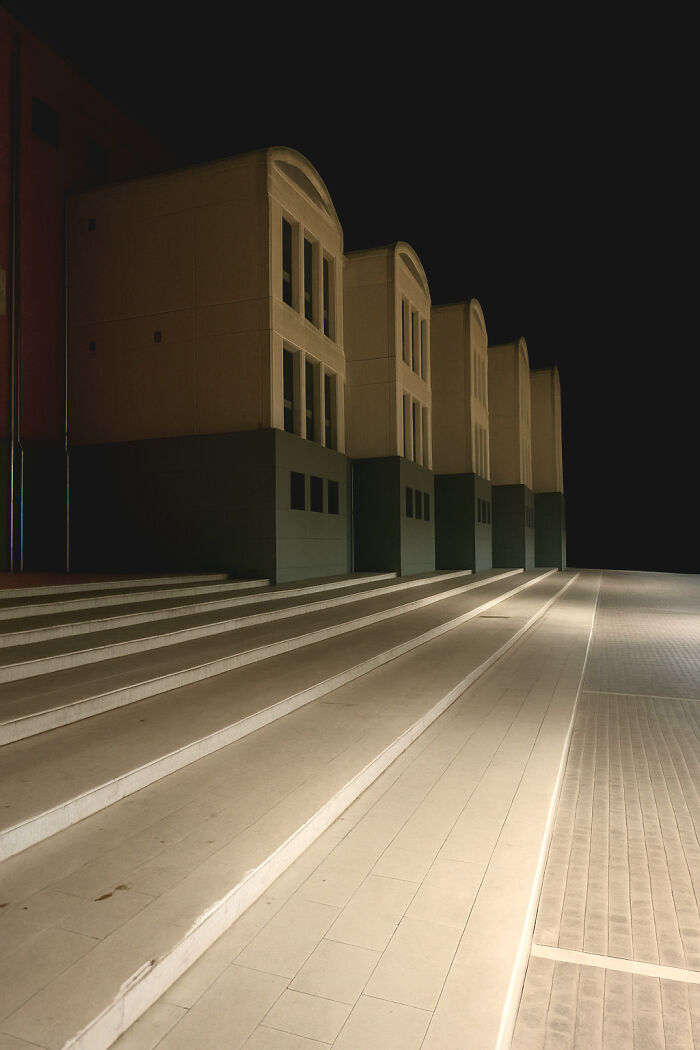 Dimly lit, empty stairway leading to repetitive buildings, evoking creepy liminal spaces that resemble the backrooms at night.