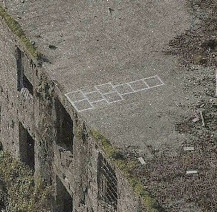 Abandoned building rooftop with faded hopscotch drawing, evoking creepy liminal spaces resembling the backrooms atmosphere.