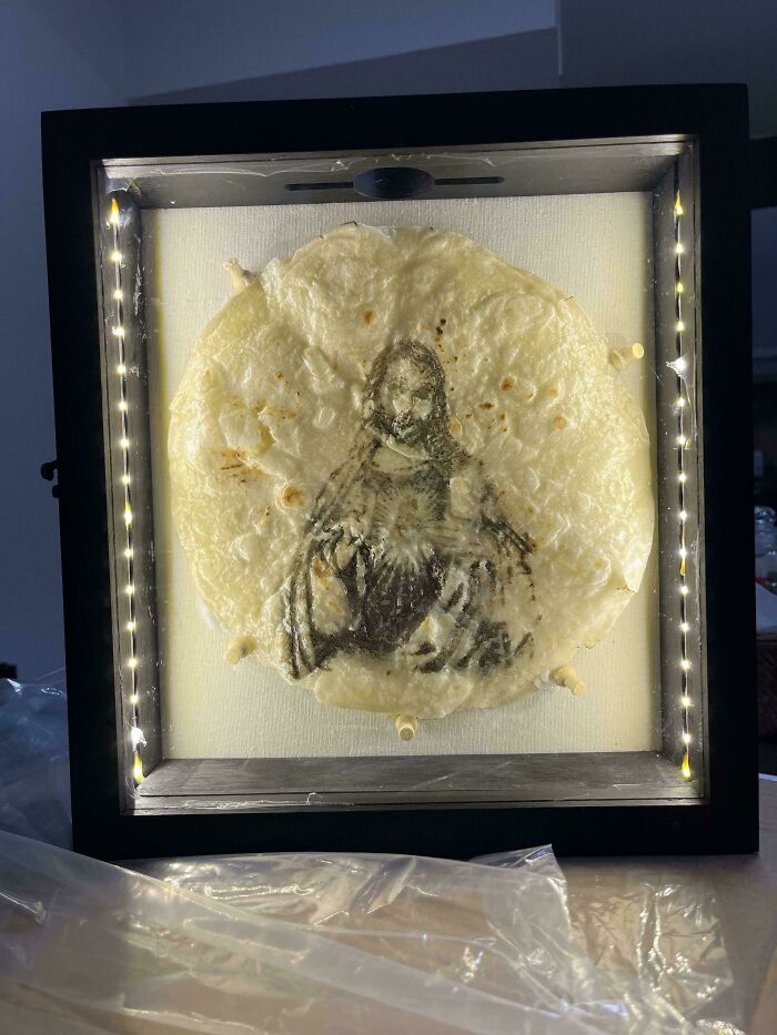 Framed unusual Christmas gift featuring a tortilla with a printed image, highlighted by LED lights in a dark room.