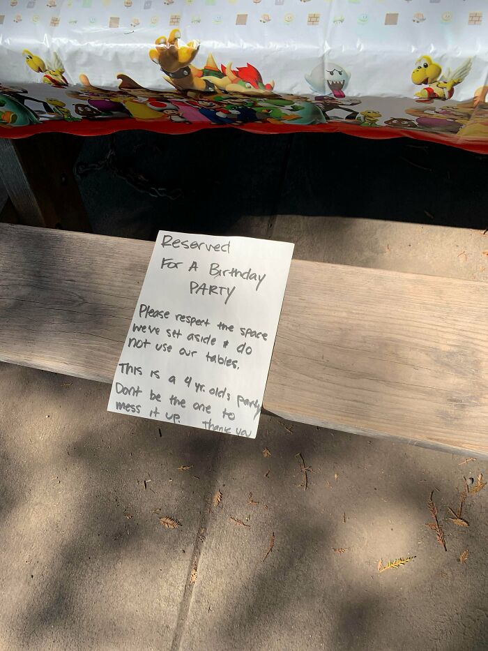 Birthday party reserved sign on park bench under themed tablecloth, example of next-level jerks