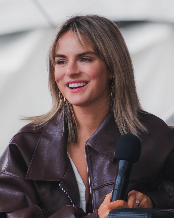 JoJo smiling and holding a microphone during an interview, showcasing her bio and career highlights.