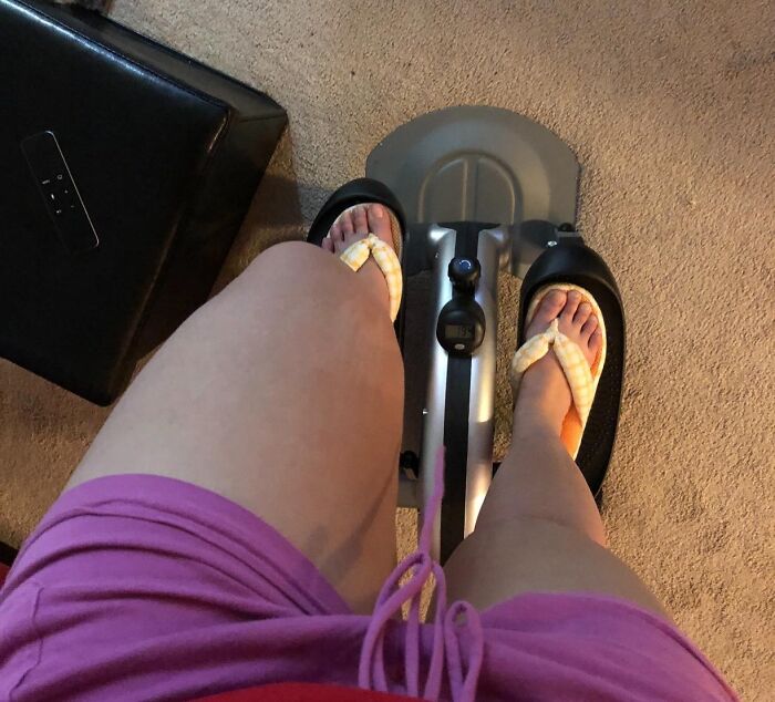 Person wearing flip-flops using a small exercise bike indoors showing apartment friendly ways to smash fitness goals.
