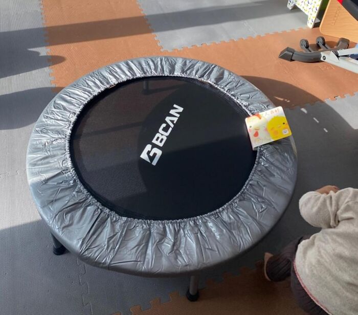 Compact indoor trampoline with protective padding on soft floor mats, ideal for apartment friendly fitness workouts.