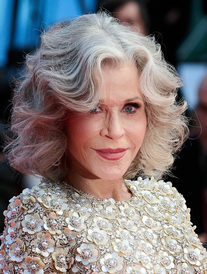 Jane Fonda with silver hair wearing a floral embellished dress at a red carpet event highlighting her bio and career.