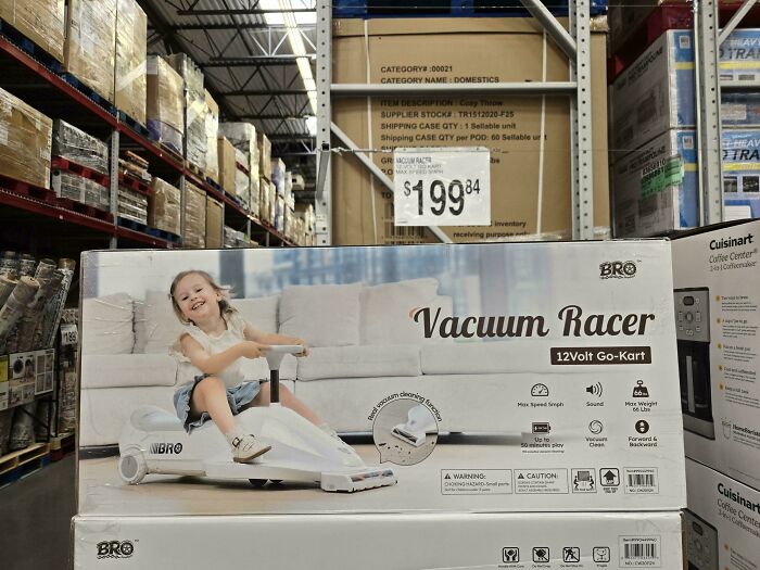 Child smiling while riding a white vacuum racer toy in a warehouse store, showcasing funny pictures capturing weirdness.