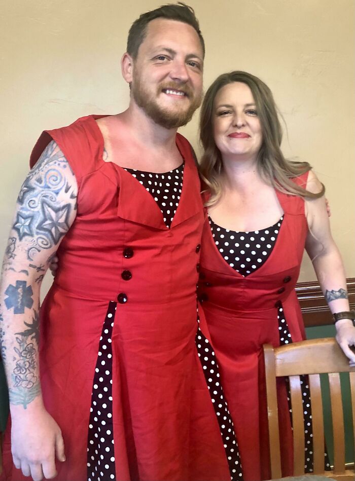 Brother and sister wearing matching red and black polka dot dresses, smiling and enjoying sibling fun together.