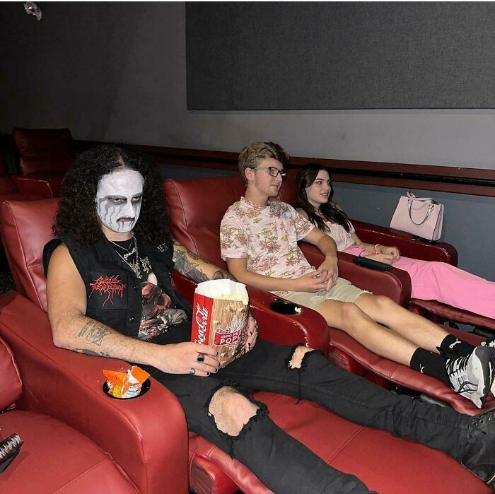 Three siblings relaxing in a theater, one wearing face paint, showcasing the fun life of having siblings.
