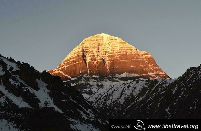 Mountain peak illuminated by golden sunlight against a clear sky, an interesting natural sight to show the internet.