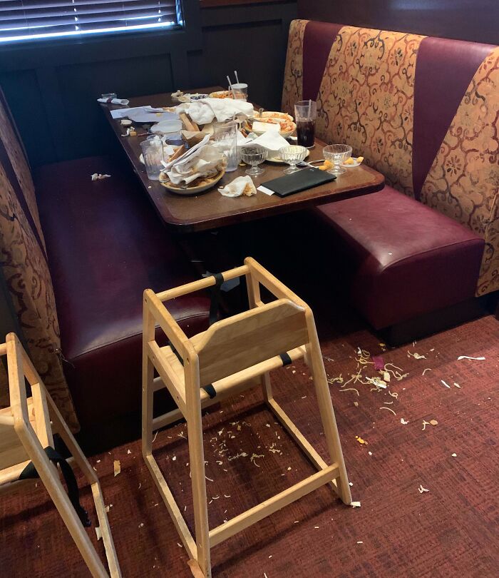 Messy restaurant booth with trash, spilled food and overturned high chairs left by next-level jerks