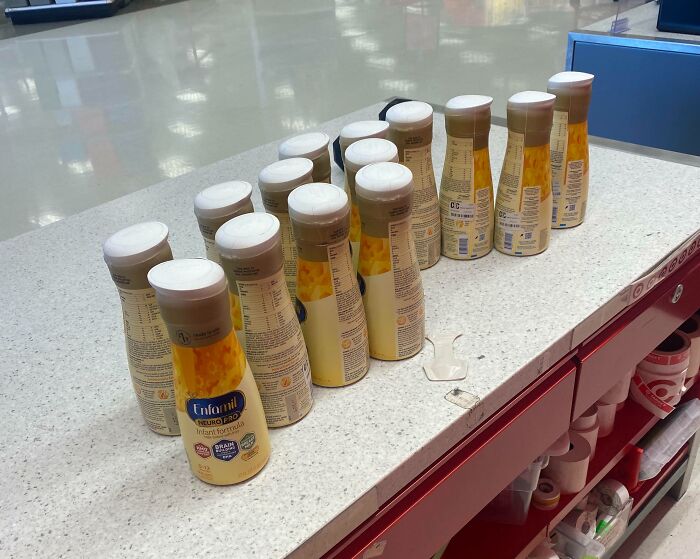 Enfamil baby formula bottles lined on a store counter, hoarded by next-level jerks