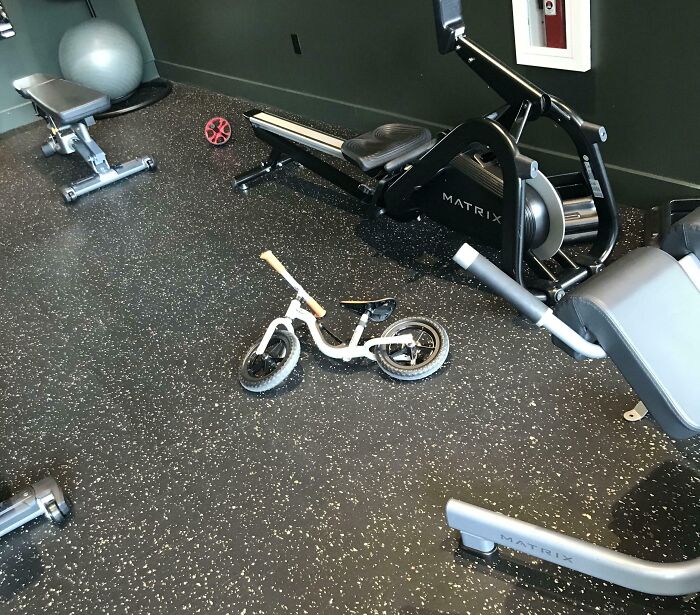 Child's balance bike left on gym floor among equipment, next-level jerks
