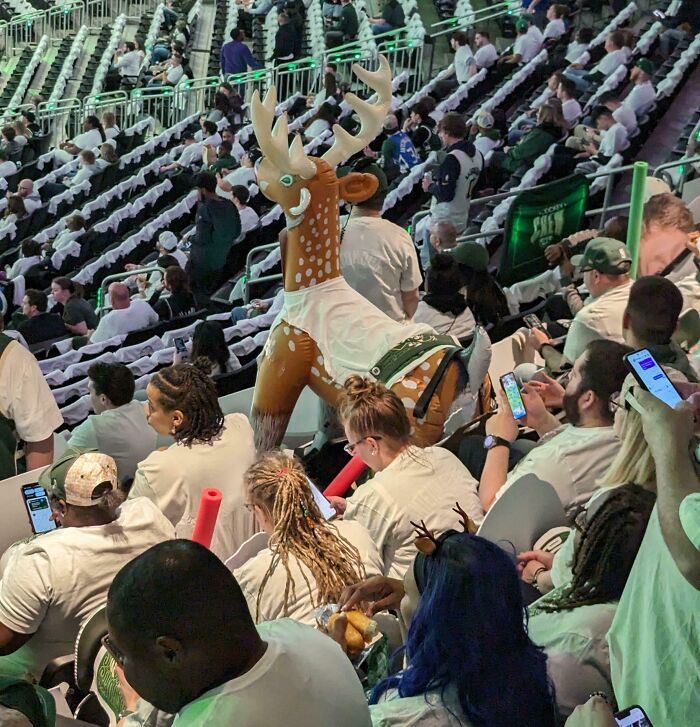Inflatable reindeer awkwardly placed among fans in packed arena, many in white shirts — next-level jerks