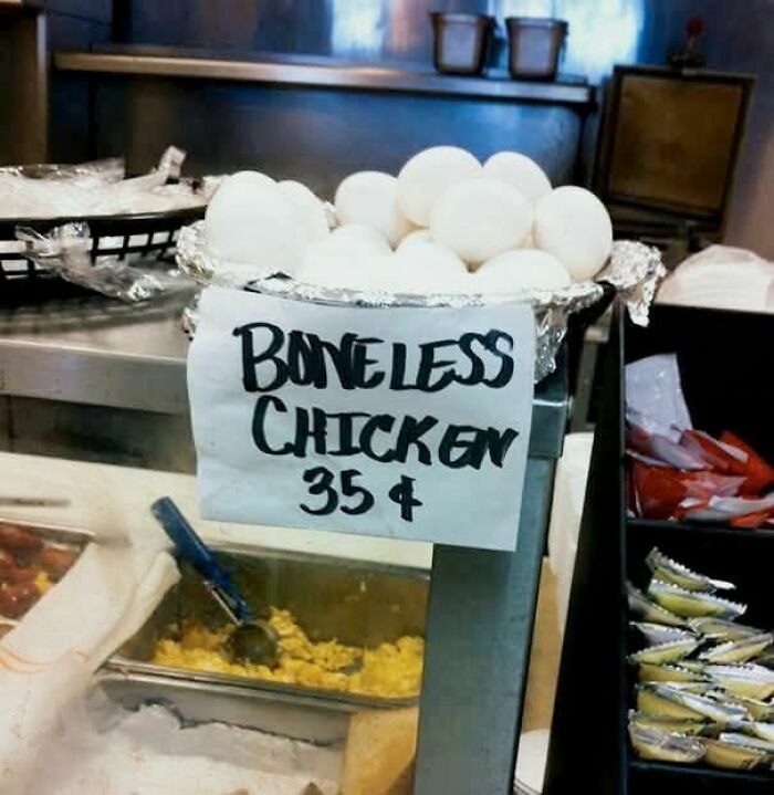 Eggs labeled as boneless chicken with a handwritten sign in a kitchen setting, showcasing funny stupid signs pics.