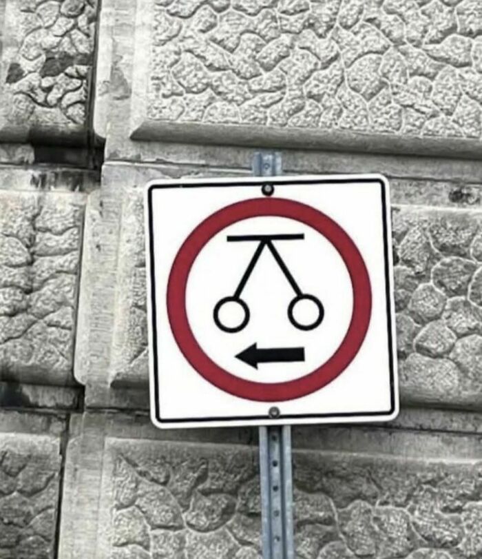 Funny stupid sign showing a nonsensical traffic symbol inside a red circle with a left-pointing arrow on a textured wall.