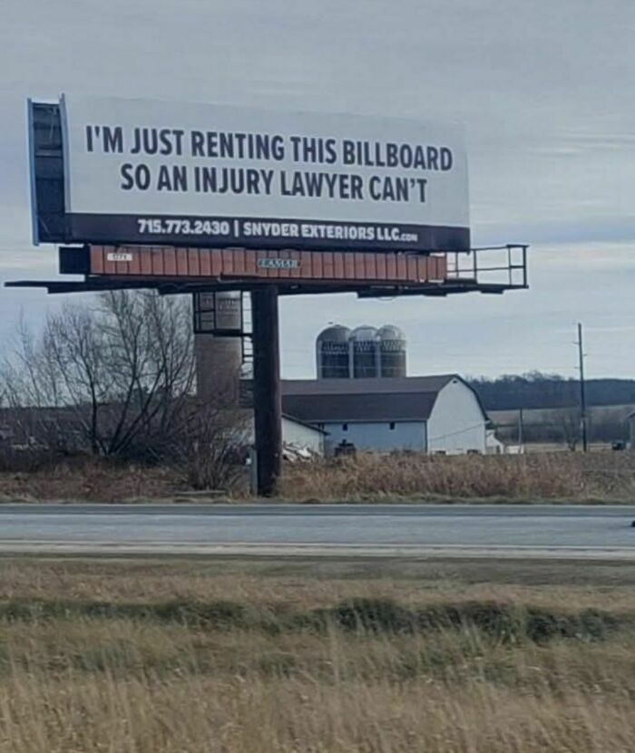 Billboard with a funny stupid sign humorously stating it is rented to keep injury lawyers away on a rural roadside.