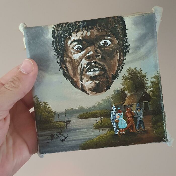 Hand holding a personalized thrifted painting with a funny unexpected giant head and small figures near a river.