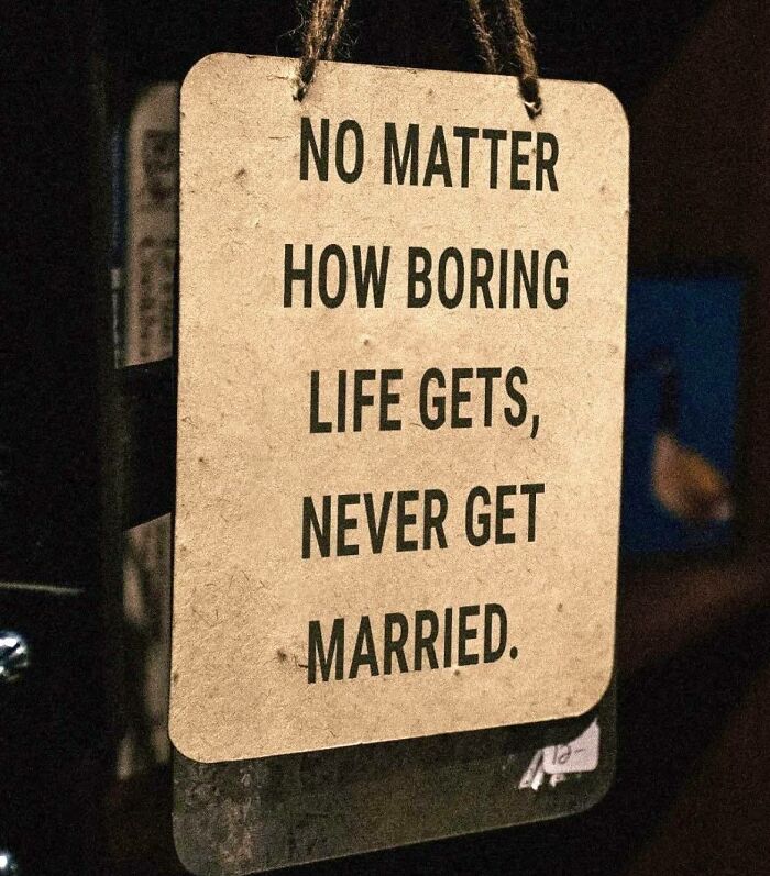 Funny stupid signs pic of a humorous hanging sign that advises never to get married despite a boring life.