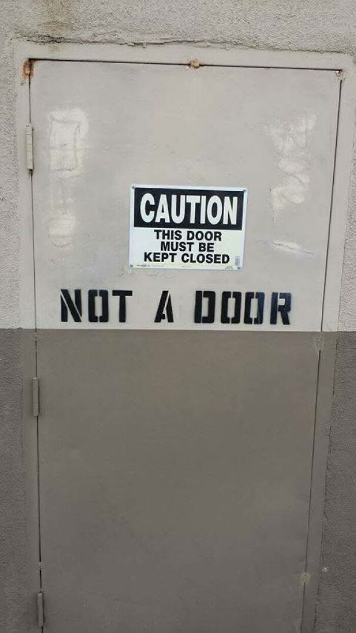 Sign on a door with a funny contradiction stating caution to keep closed but also saying not a door in funny stupid signs pics.