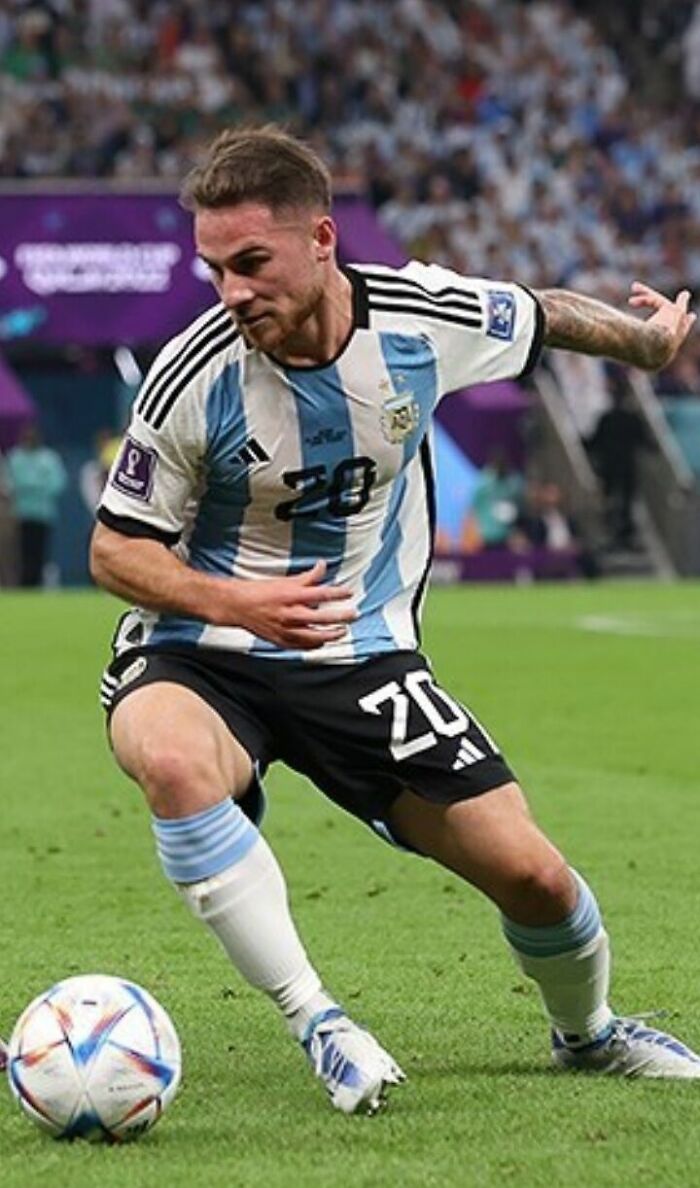 Alexis Mac Allister wearing Argentina jersey controlling the ball during an intense soccer match on the field.