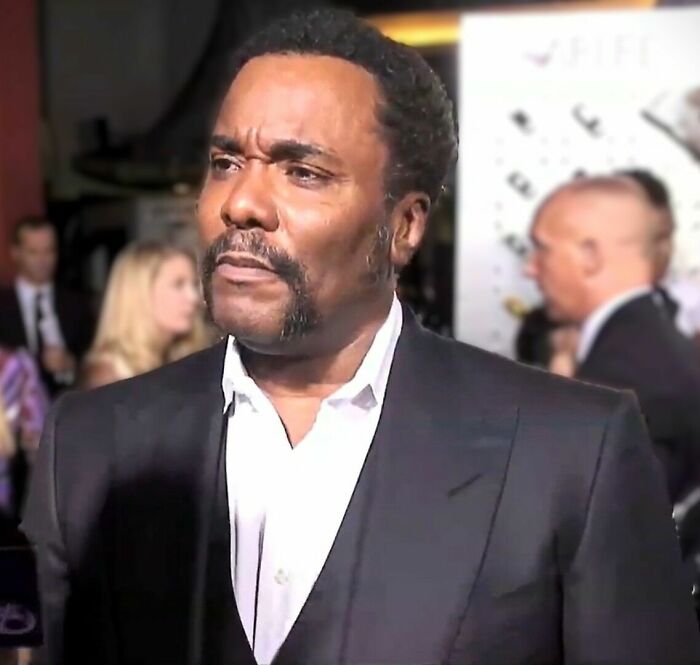 Lee Daniels at an event, wearing a dark suit and white shirt, captured in a candid moment highlighting his career.