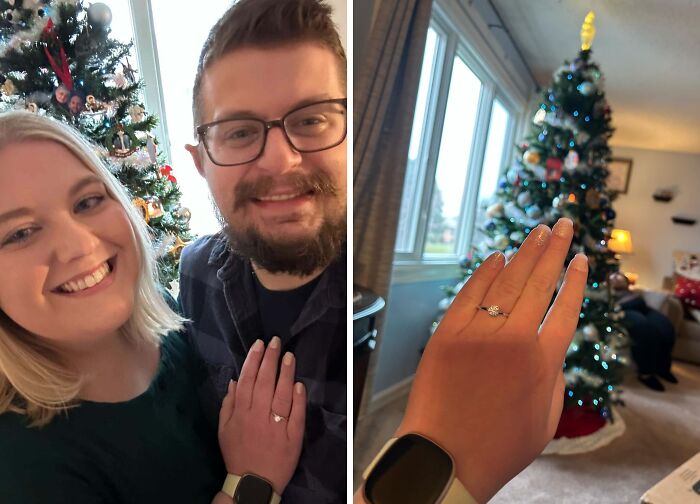 Couple smiling by a Christmas tree, showing an engagement ring in a cozy living room during holiday moments.