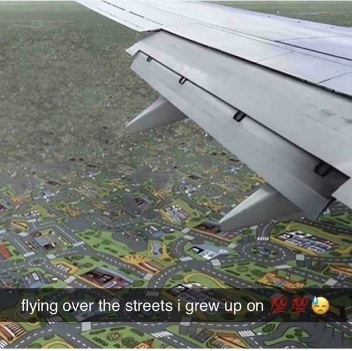 View from airplane wing over a play mat with roads and buildings, evoking 90s and 2000s nostalgia childhood memories.