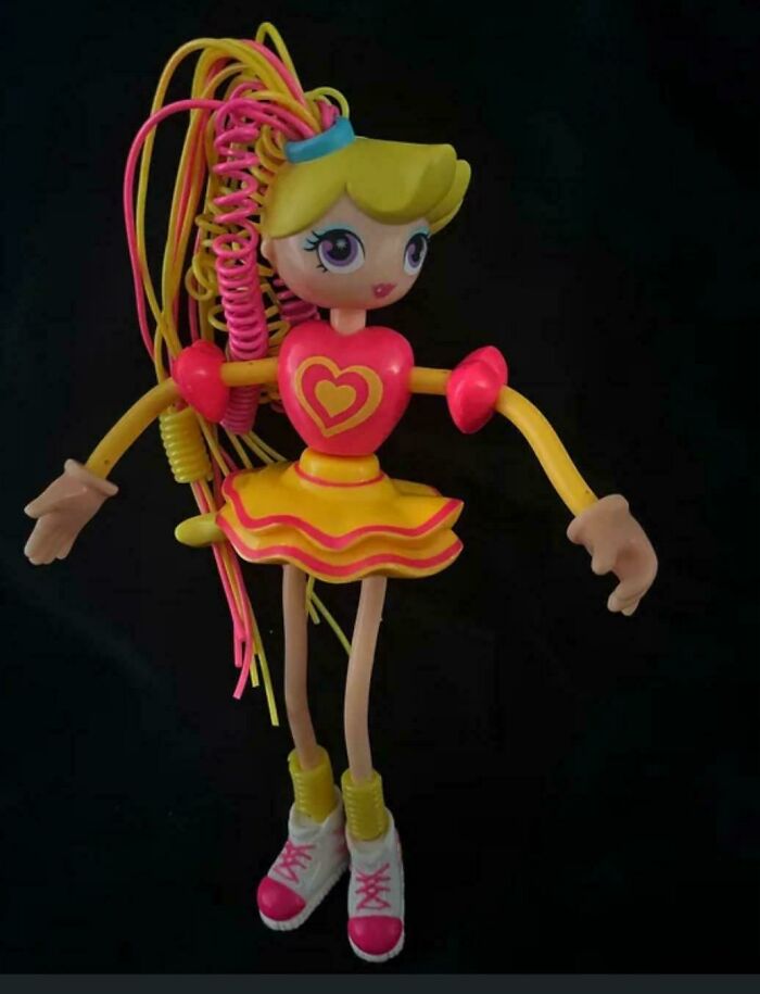 90s and 2000s nostalgia toy doll with colorful hair and outfit, bright pink and yellow against a black background
