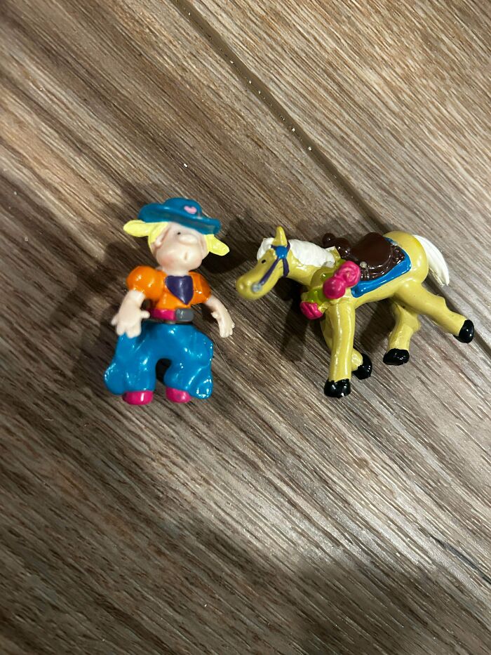 Small plastic cowboy figure and toy horse on wooden floor representing 90s and 2000s nostalgia childhood memories.