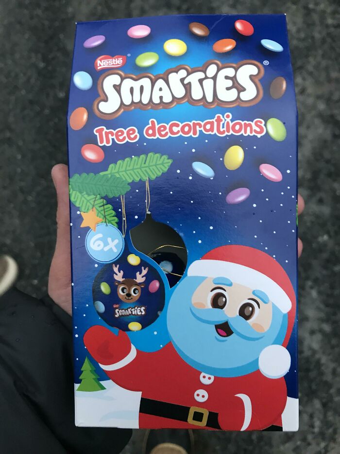 Smarties tree decorations box held in hand showing a broken ornament, an example of bad Secret Santa gifts.