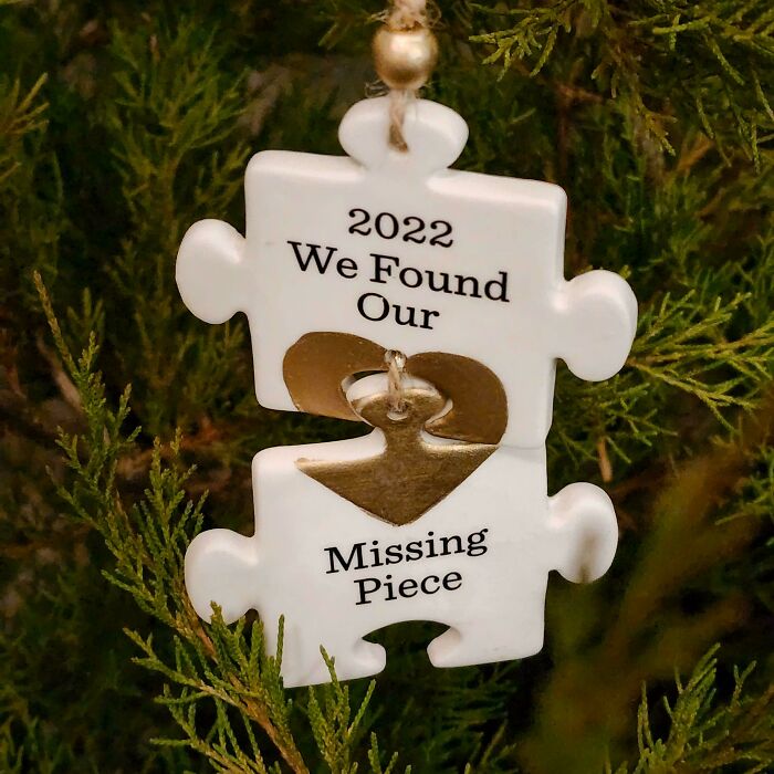 Holiday moments ornament shaped like puzzle pieces with a heart hanging on a Christmas tree branch.