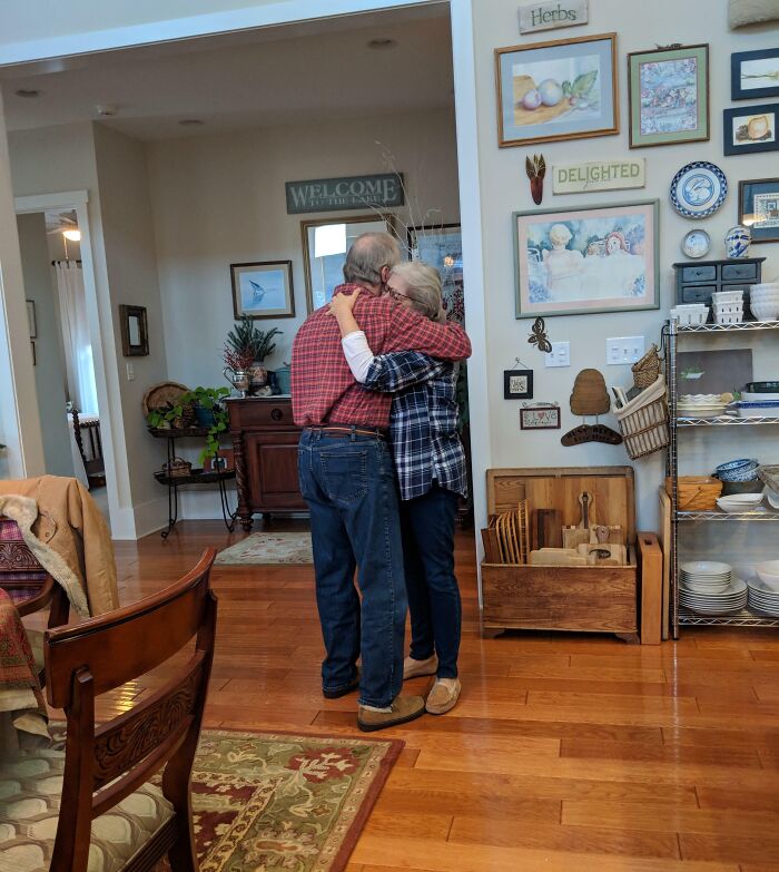 Elderly couple sharing a warm hug in a cozy kitchen, capturing a sweet holiday moment to melt hearts.