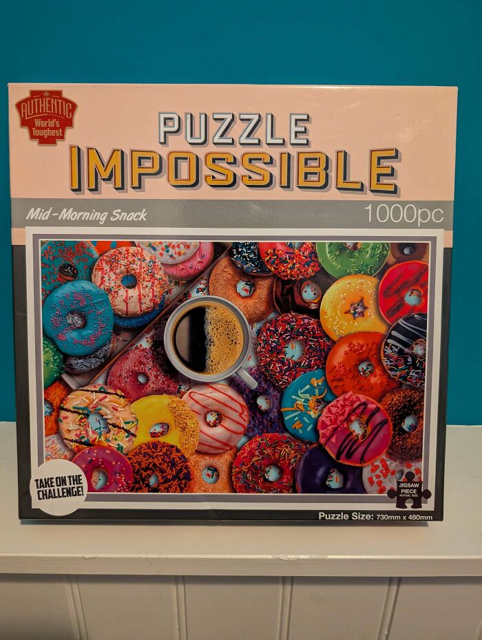 Box of an impossible 1000-piece donut puzzle as a hilariously bad Secret Santa gift challenge on a shelf against a blue wall.