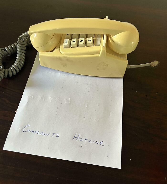 Old beige rotary phone labeled complaints hotline on a paper, capturing funny pictures from 2025 weirdness.
