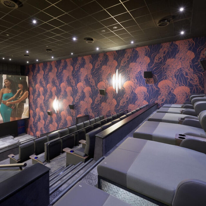 Modern movie theater with reclining loungers and jellyfish patterned walls, showcasing impressive country innovations.