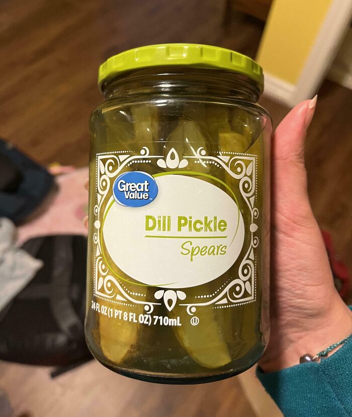 Hand holding a jar of Great Value dill pickle spears, an example of hilariously bad Secret Santa gifts.