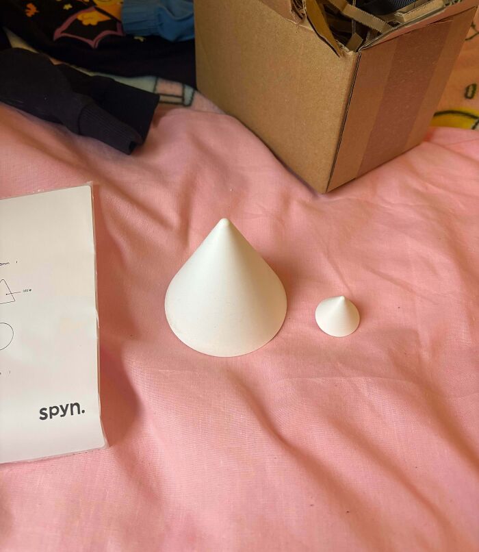 Two white cone-shaped objects on a pink surface next to a cardboard box and a paper, illustrating bad Secret Santa gifts.