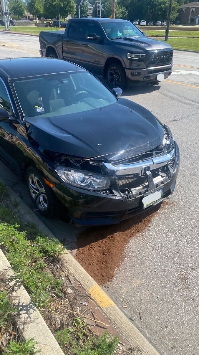 Black sedan with severe front-end damage parked by the curb, illustrating entitled person behavior in 2025 scenarios.