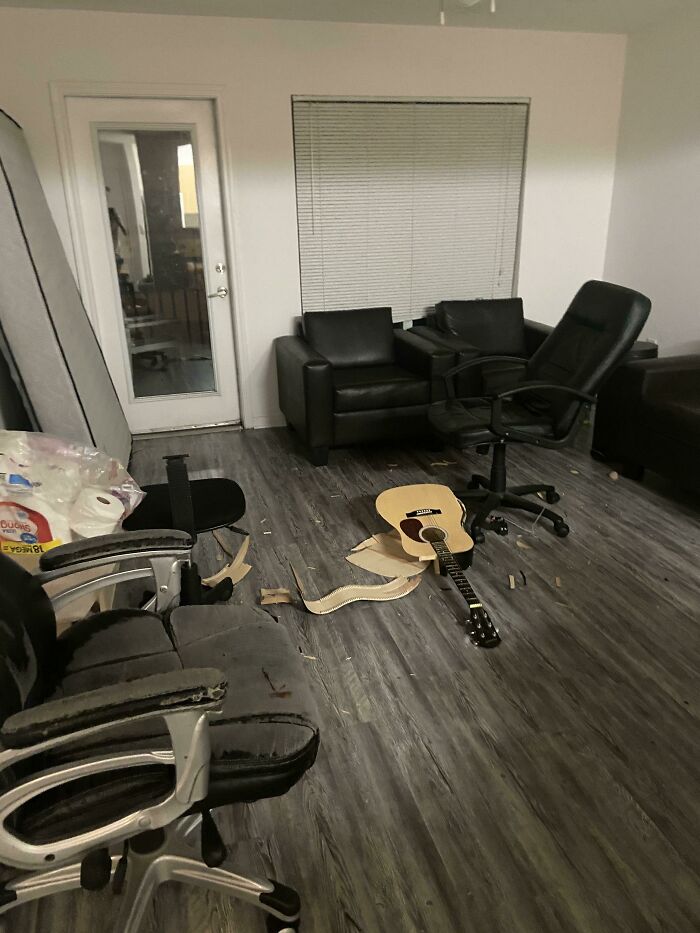 Living room with damaged furniture and a broken guitar, illustrating entitled person behavior and neglect in 2025.