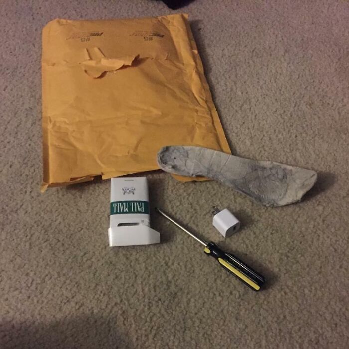 Used sock, screwdriver, phone charger adapter, and a small mail holder received as hilariously bad Secret Santa gifts.
