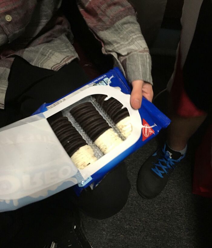 Person holding an ill-fitting pack of cookies showing hilariously bad Secret Santa gifts people have actually received.