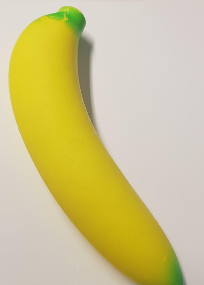 Bright yellow banana-shaped item with green tips on a plain white surface, an example of bad Secret Santa gifts.