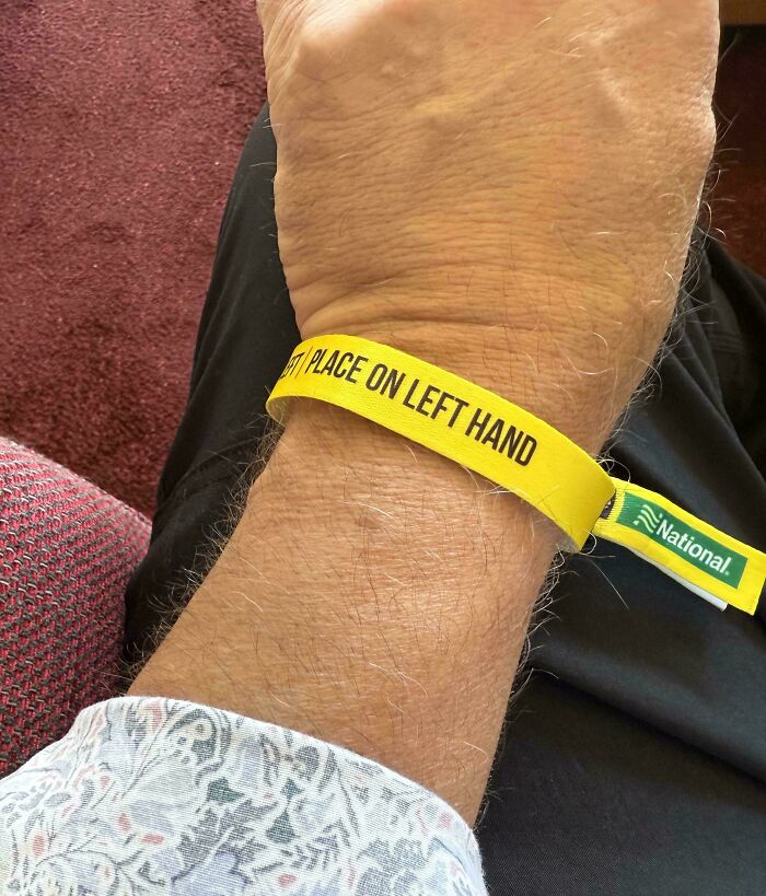 Close-up of a wrist with a yellow band instructing to wear on the left hand, one of the impressive things countries implemented.