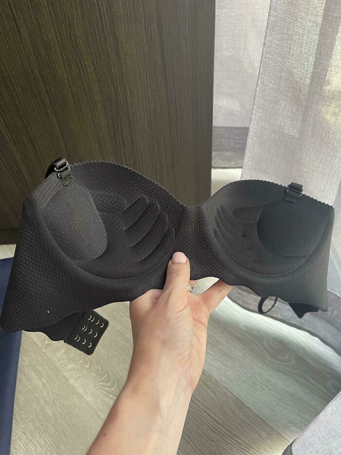 Hand holding a black bra with molded cups indoors, illustrating men share things they learned about women from relationships.