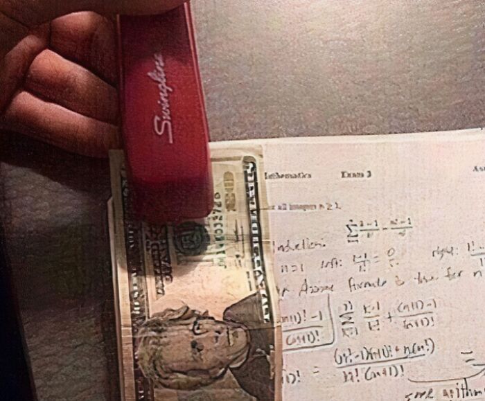 Hand holding a red stapler stapling a dollar bill to a math homework page in random pics that make you laugh.