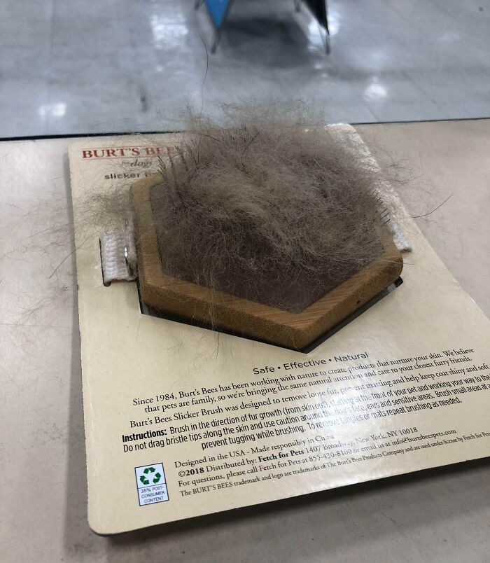 Slicker pet brush over packaging piled with fur on table, a photo of next-level jerks