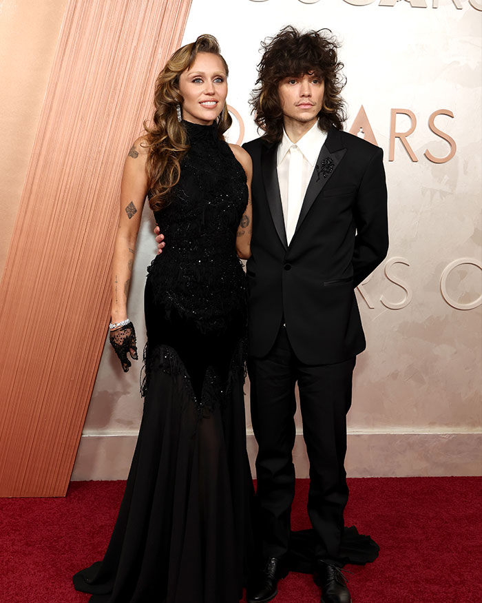 Miley Cyrus and Maxx Morando posing on the red carpet, engagement sparking mixed reactions about age difference. Miley Cyrus and Maxx Morando posing on the red carpet, engagement sparking mixed reactions about age difference.