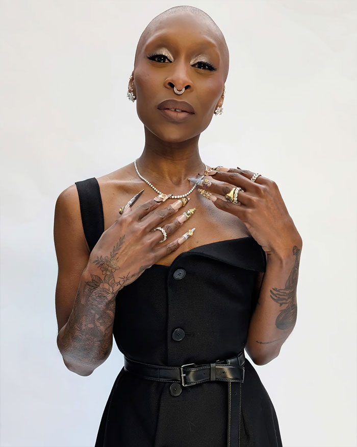 Cynthia Erivo posing with elaborate rings and manicured nails, highlighting her oddly large hands in a black dress. Cynthia Erivo posing with elaborate rings and manicured nails, highlighting her oddly large hands in a black dress.