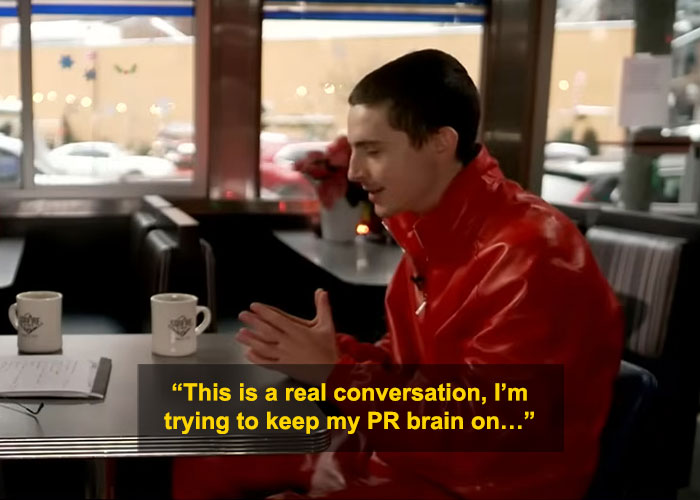 Timoth&eacute;e Chalamet in red jacket during interview, facing criticism for perceived arrogance in public appearance.