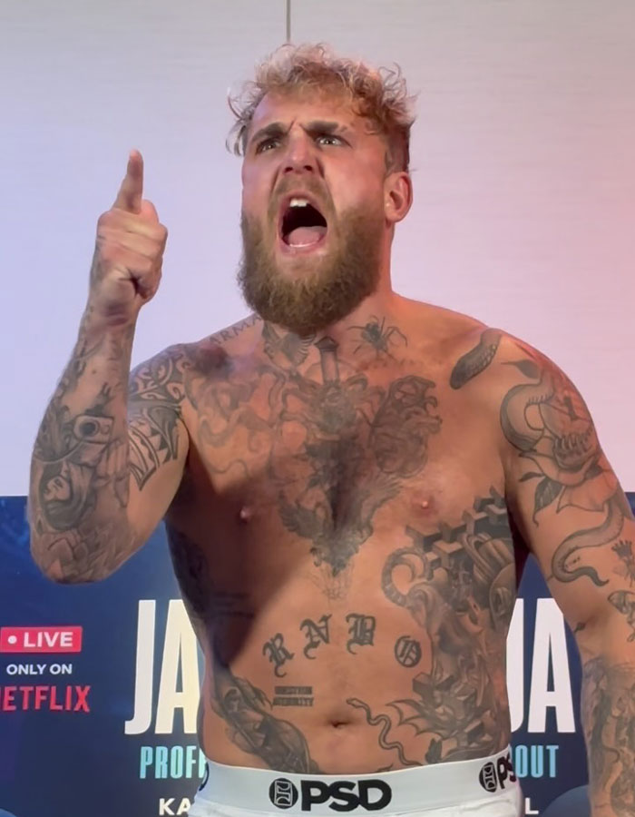 Jake Paul shirtless and tattooed, shouting with a raised finger during a live event. Jake Paul shirtless and tattooed, shouting with a raised finger during a live event.