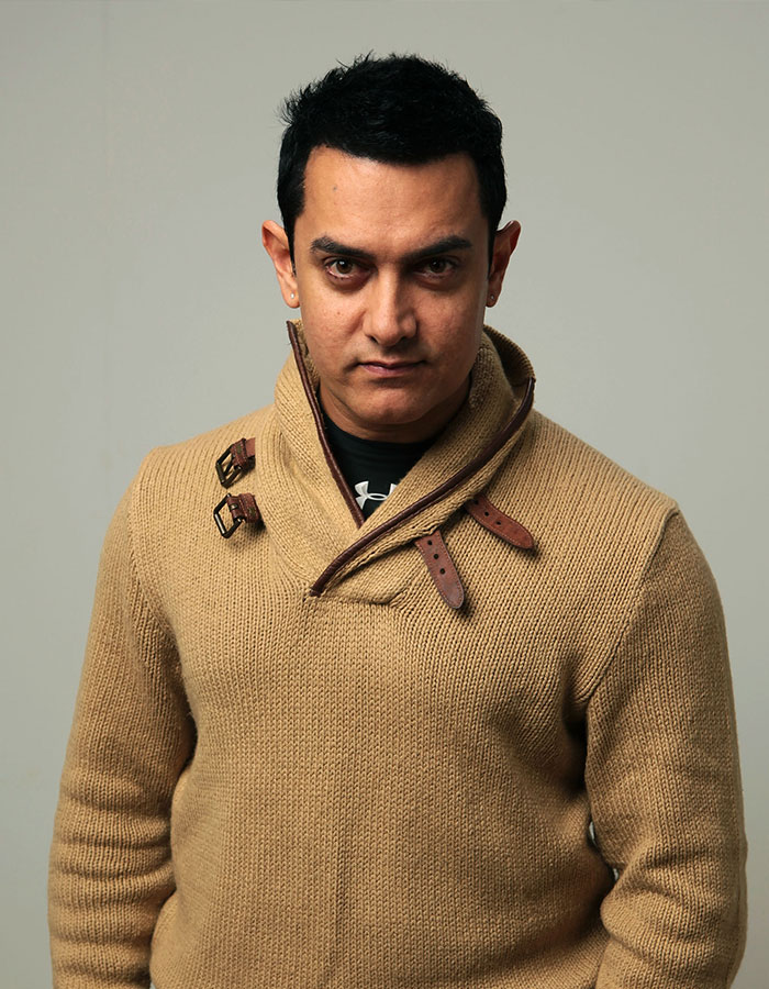 Male actor in a tan sweater with buckles, portraying confidence amid outrageous demands actors have put in contracts.